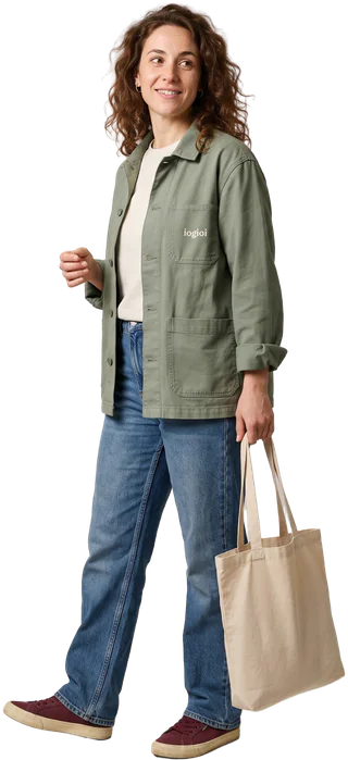 La Cara de Siempre: Mujer de pelo castaño rizado con chaqueta de trabajo verde salvia y vaqueros, con una bolsa de lona